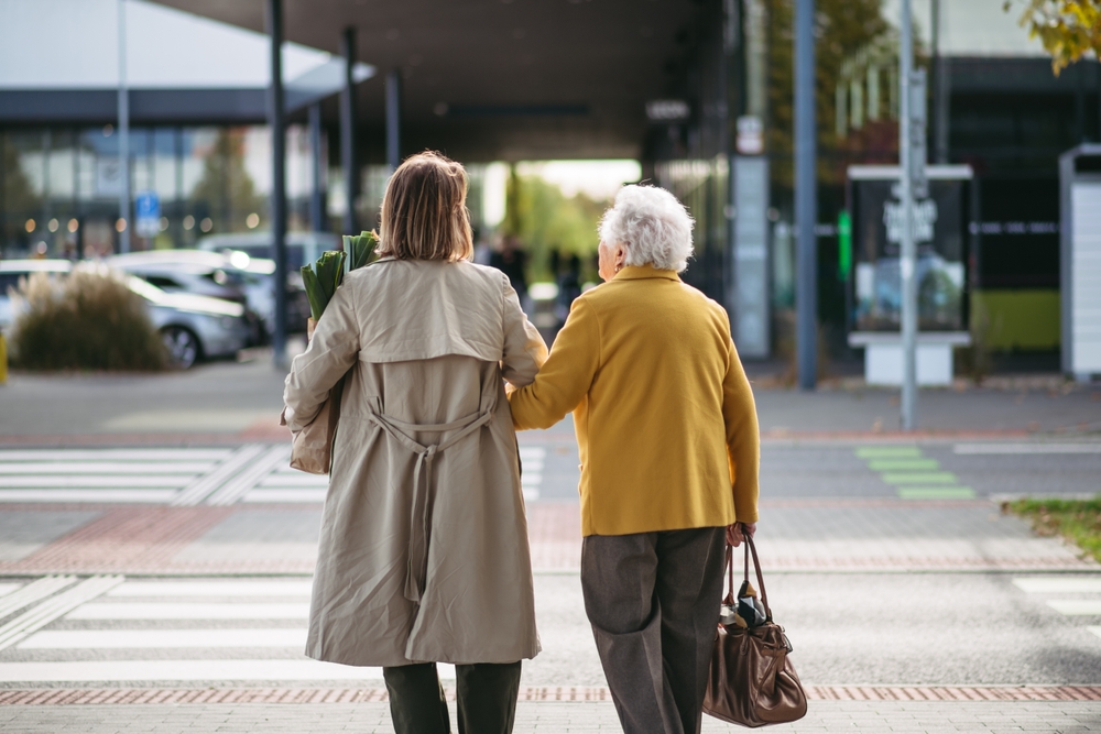 Caregiver walking senior in assisted living near San Dimas, CA