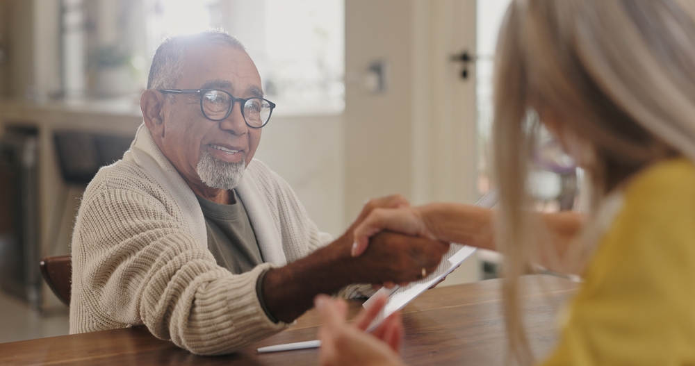 Senior shaking hands in two bedroom assisted living apartments.