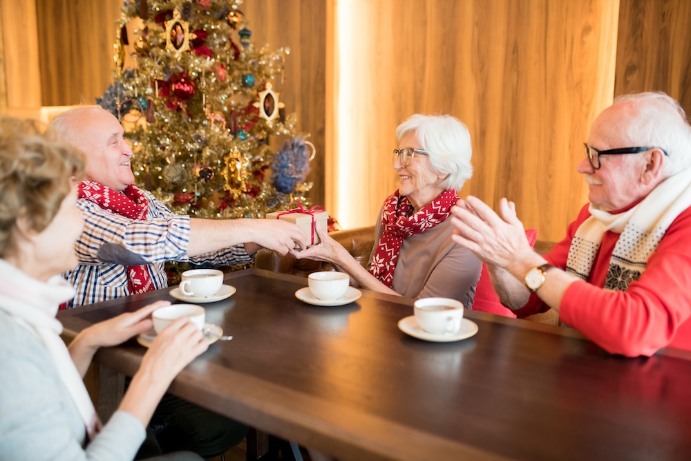 Seniors around a table exchanging gifts and enjoying senior living san gabriel valley